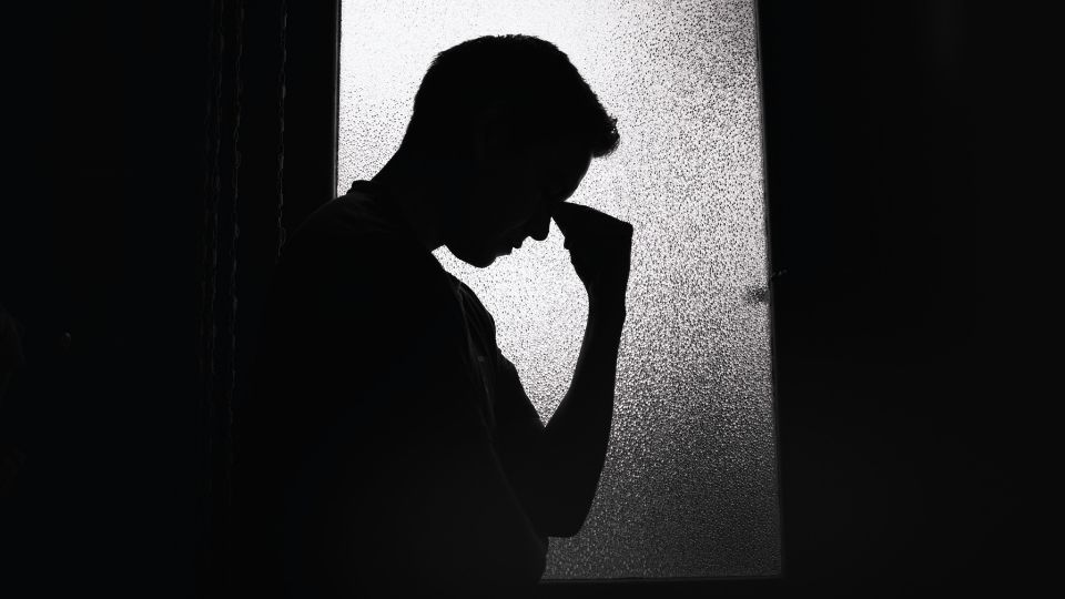 a man stands in the dark after showing signs of drinking