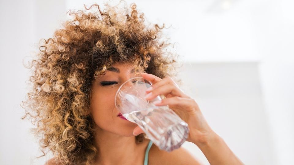 a woman with alcohol use disorder drinks a glass of water